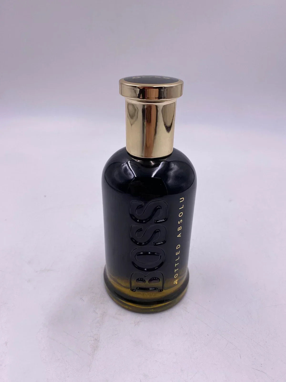 Hugo Boss BOSS Bottled Absolu Intense men's fragrance bottle, 3.3 oz, with sleek design and gold accents, on a neutral background.